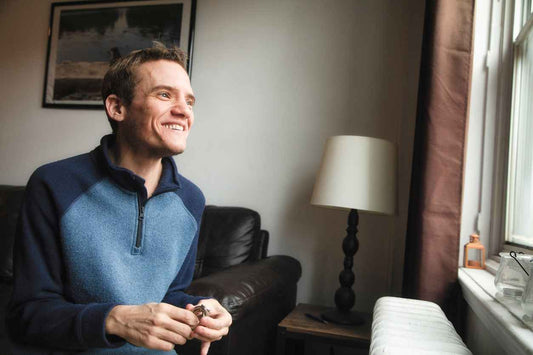 Young adult male with asperger's syndrome smiling out the window in his home.