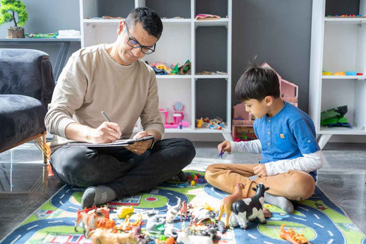 A professional child psychologist observing a little boy with autism playing with toys