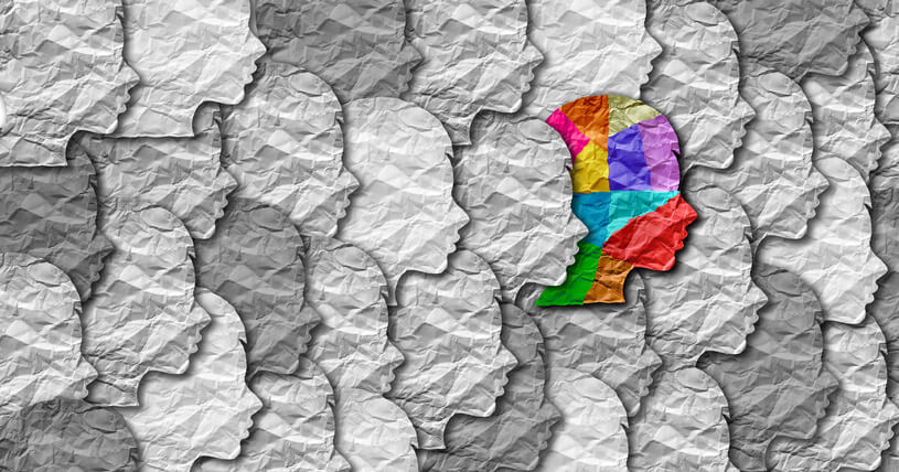 cut out paper faces with one multicolored one among many colorless ones